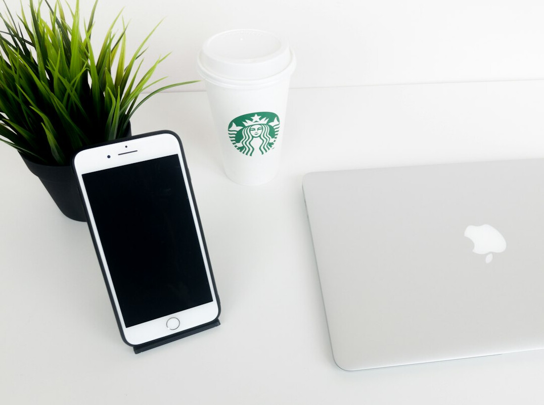 Laptop, notebook and coffee cup on a bright wooden desk
